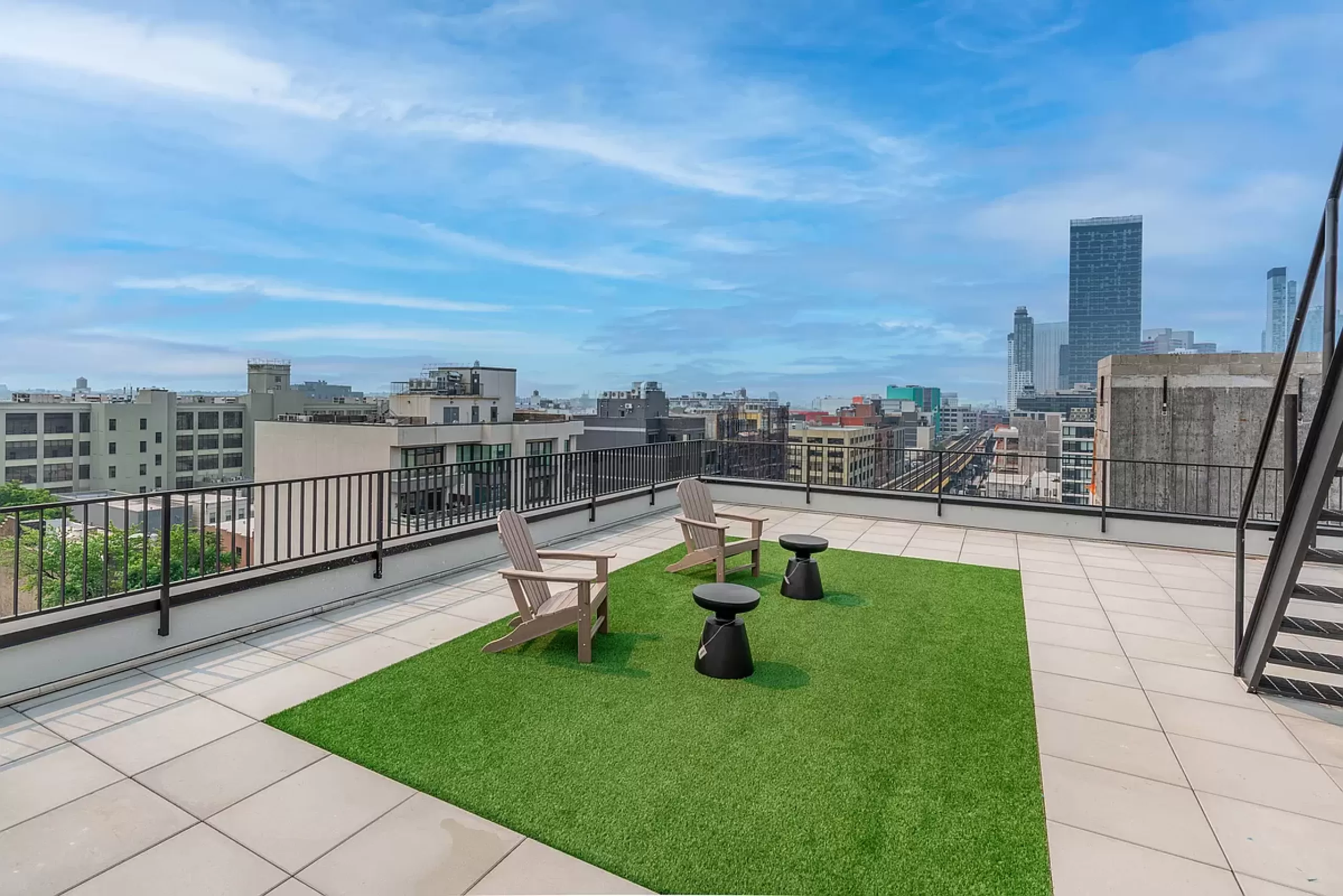 Project 3610, a modern rooftop terrace by Total Building Solutions, featuring wooden Adirondack chairs, artificial grass, and a stunning cityscape view.